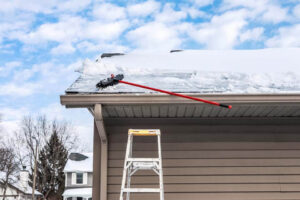 homeowner trying to prevent ice dams by brushing snow off roof