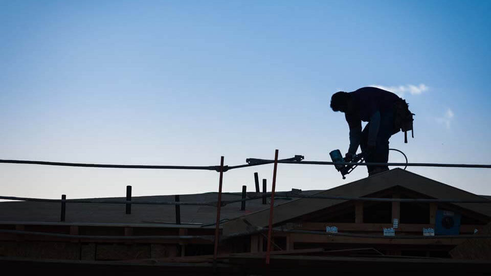 worker repairing roof leak at dusk